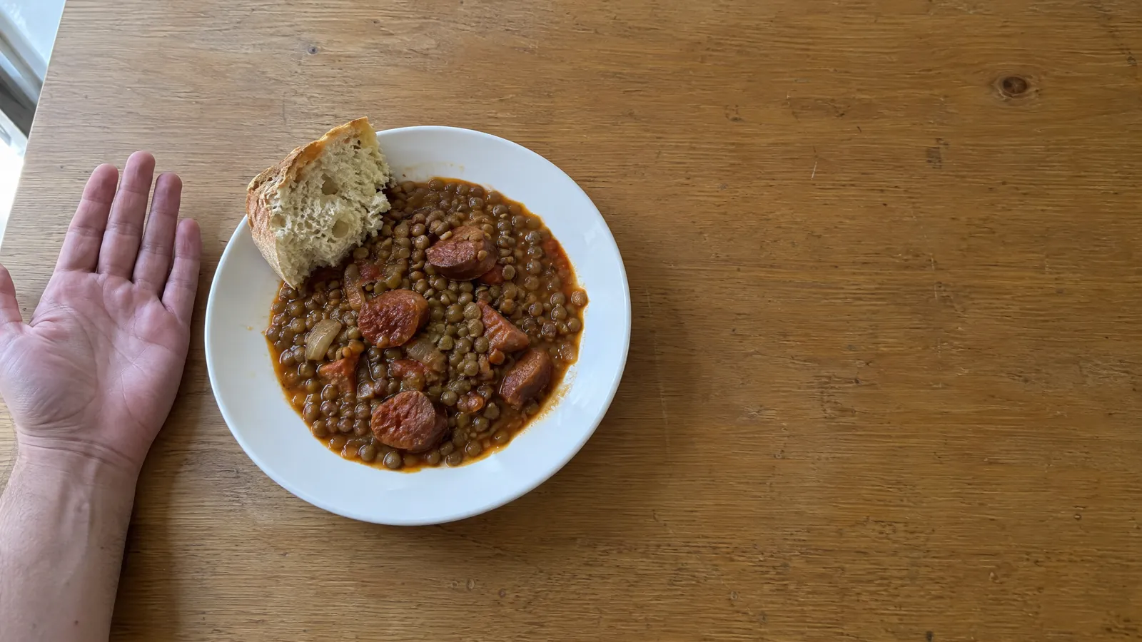 Una mano abierta con la palma hacia arriba junto a un plato de comida.