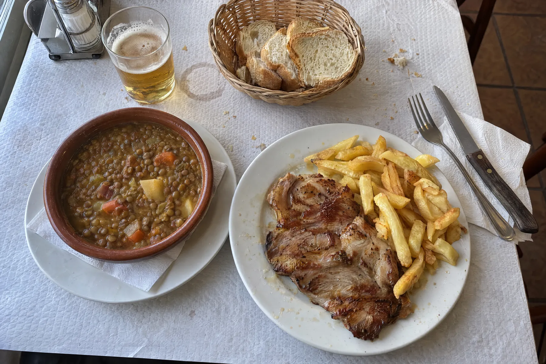 Un menú del día servido en la mesa: primero, segundo, pan y bebida.